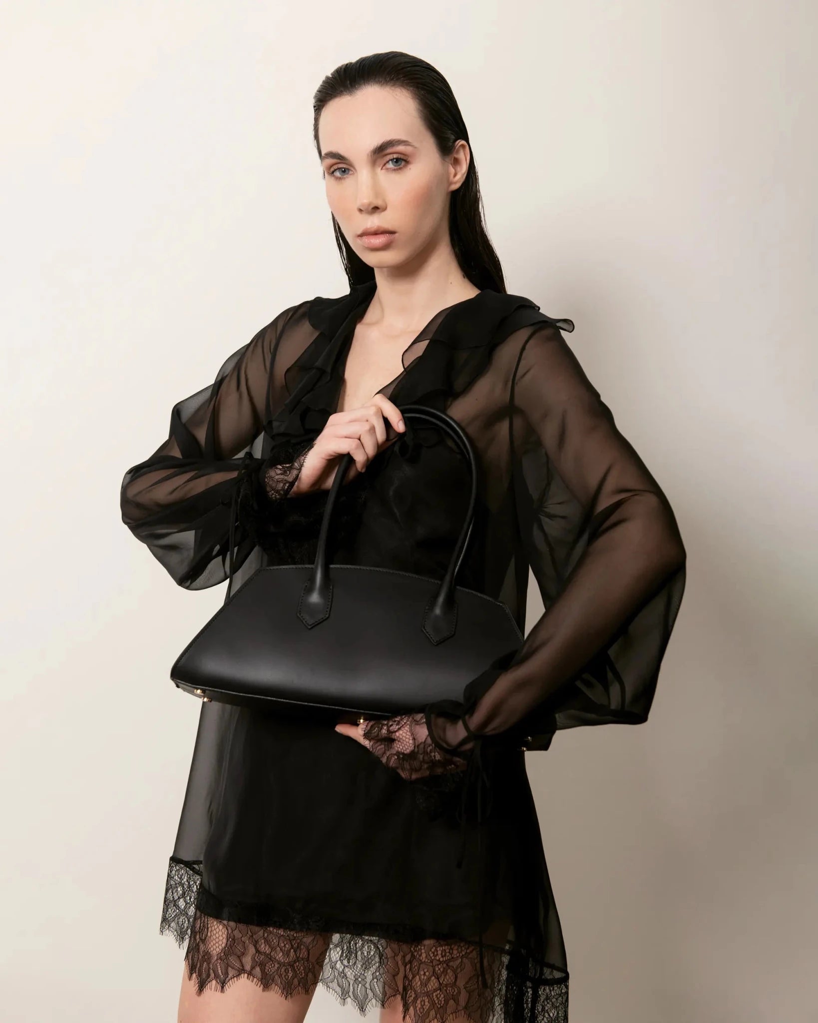 Modella con Bellucci in pelle nera, abito nero trasparente elegante vista frontale