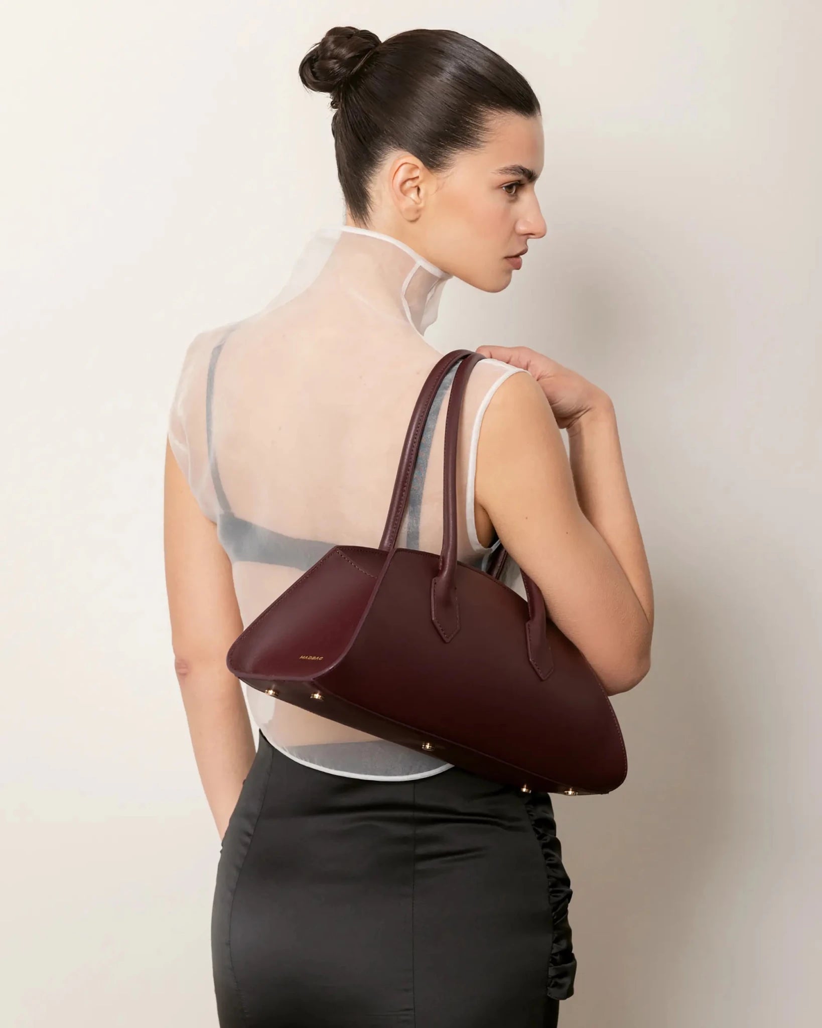 Modella con Bellucci MADBAG in pelle color bordeaux portata a spalla, vista posteriore elegante