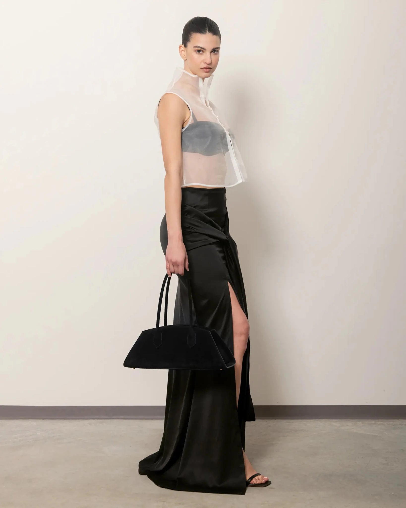 Modella con Bellucci MADBAG in suede nero, vista laterale con abito lungo nero