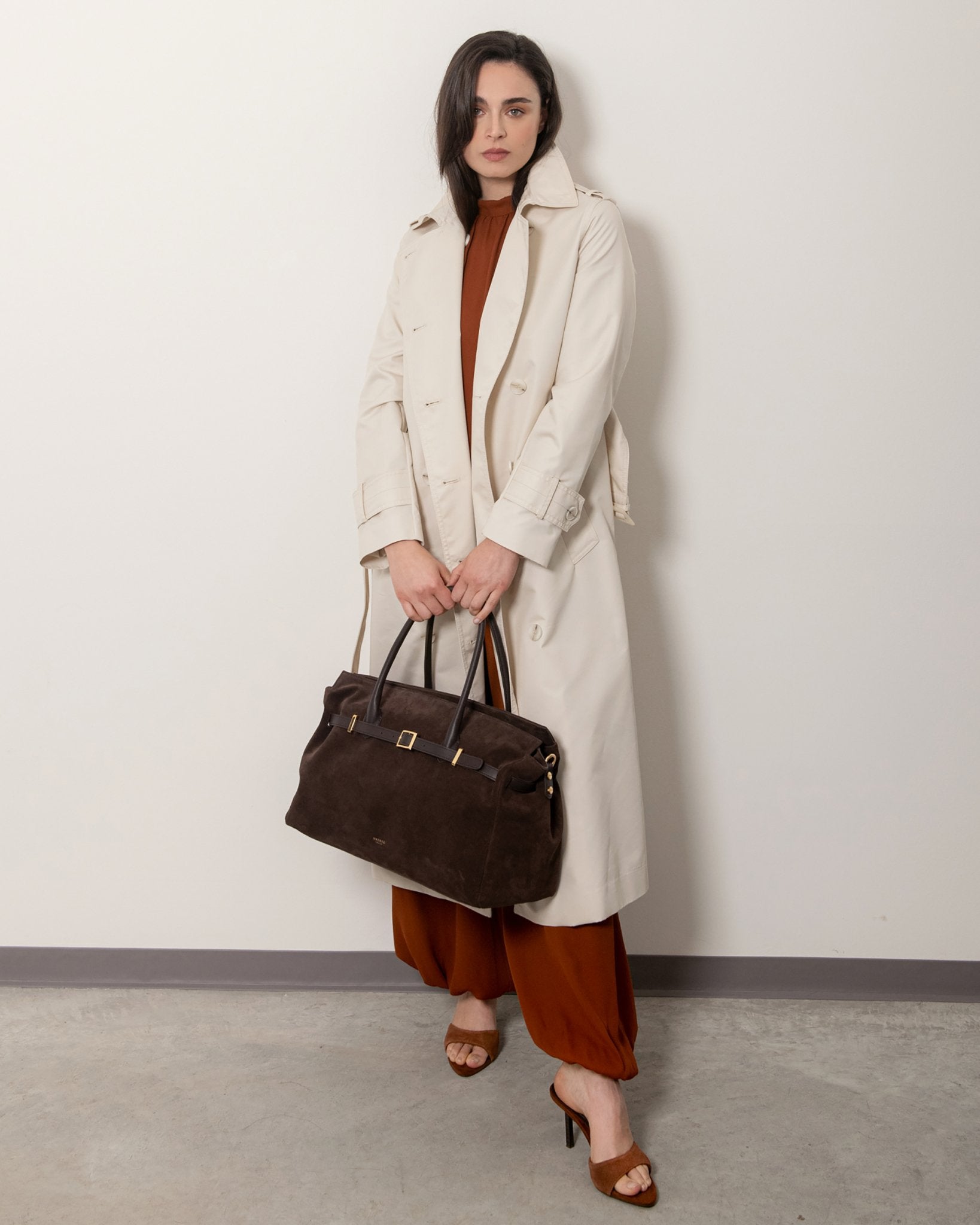 Borsa Bellucci in pelle marrone con finiture oro, abbinata a trench beige, borsa di lusso Made in Italy