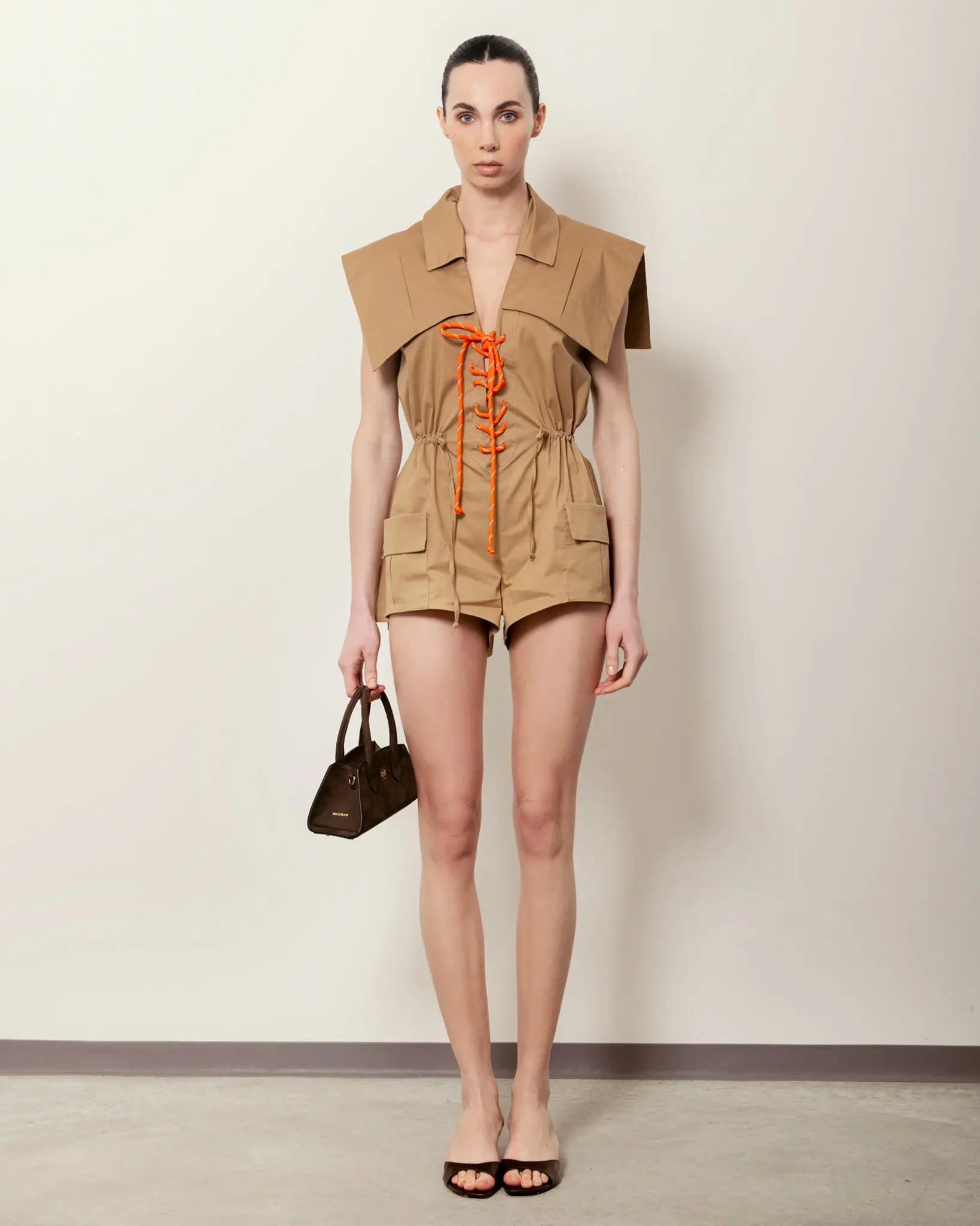 Modella con Small Bassotto MADBAG in pelle nabuk marrone, look estivo beige full body