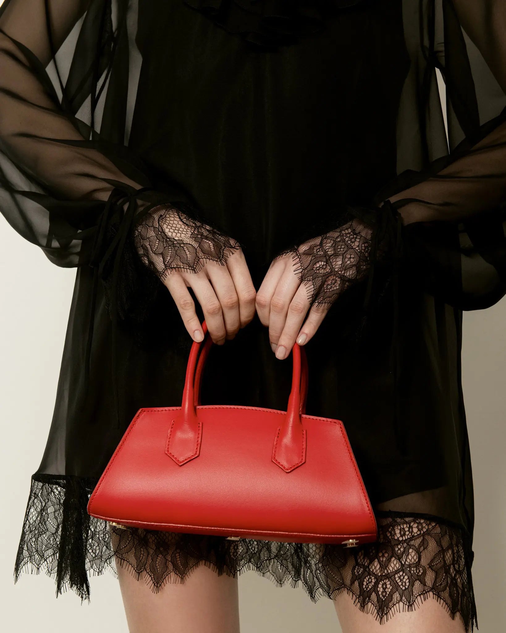 MADBAG Small Bassotto red leather handbag held by model with black lace dress