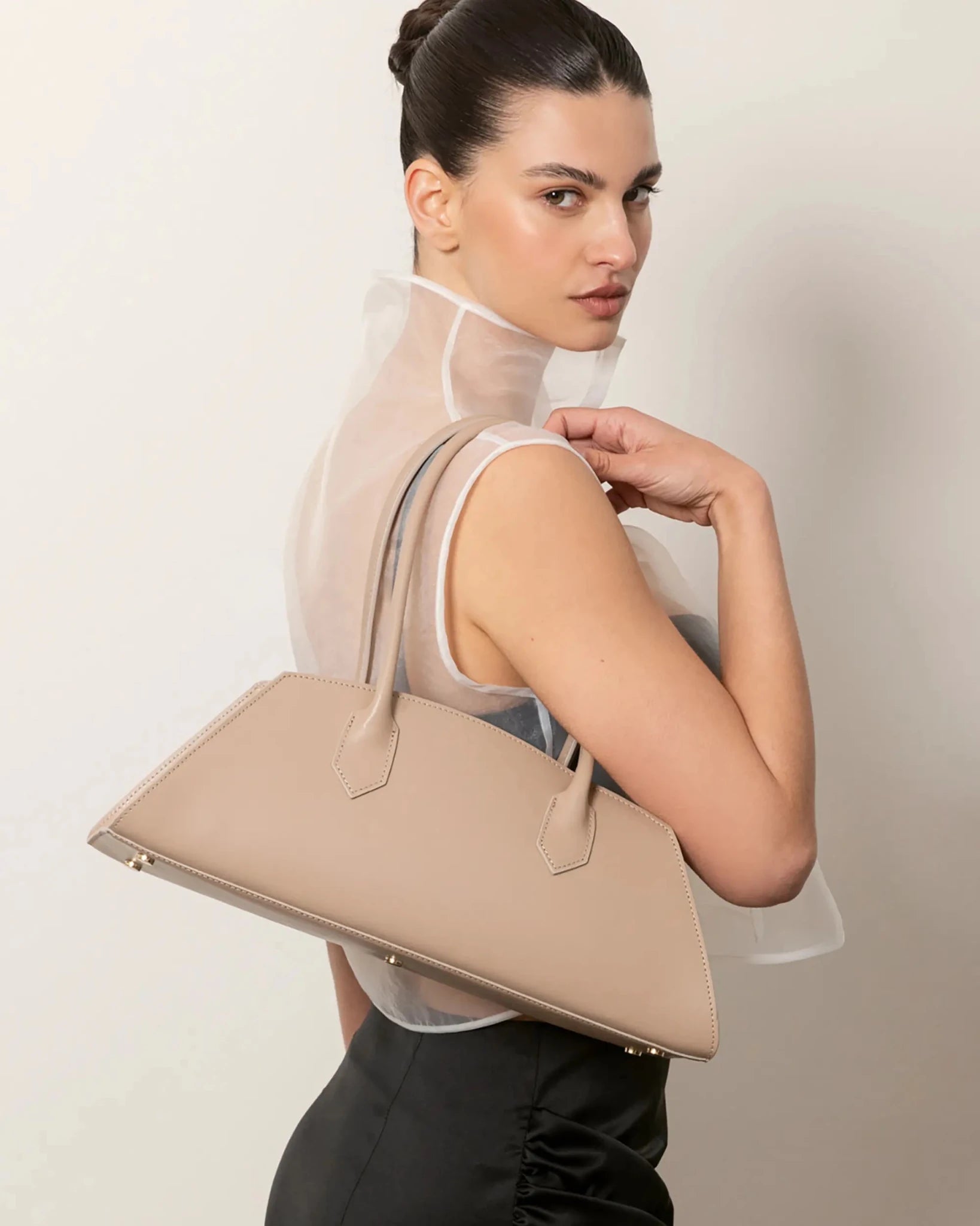 Modella con Small Bassotto in pelle liscia color taupe, dettaglio borsa sulla spalla